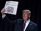 Americký prezident Donald Trump na slavnostní snídani ukazoval výtisky novin....