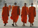 Buddhistití mnii s respiraními roukami v ulicích Phnompenhu v Kambode....