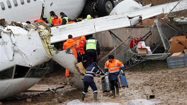 Pracovnci ostrahy po nehod Boeingu 737-86J z vraku vyndavali i zavazadla cestujcch. (6. nora 2020)