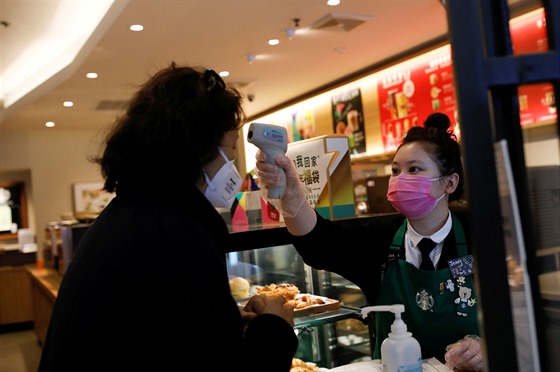 Zaměstnankyně kavárny Starbucks v Pekingu měří nově příchozí zákaznici teplotu....