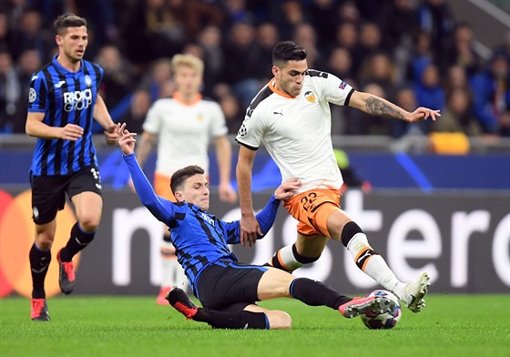 Mattia Caldara z Atalanty Bergamo skluzem bere mí Maximu Gomezovi z Valencie.