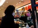Zaměstnankyně kavárny Starbucks v Pekingu měří nově příchozí zákaznici teplotu....