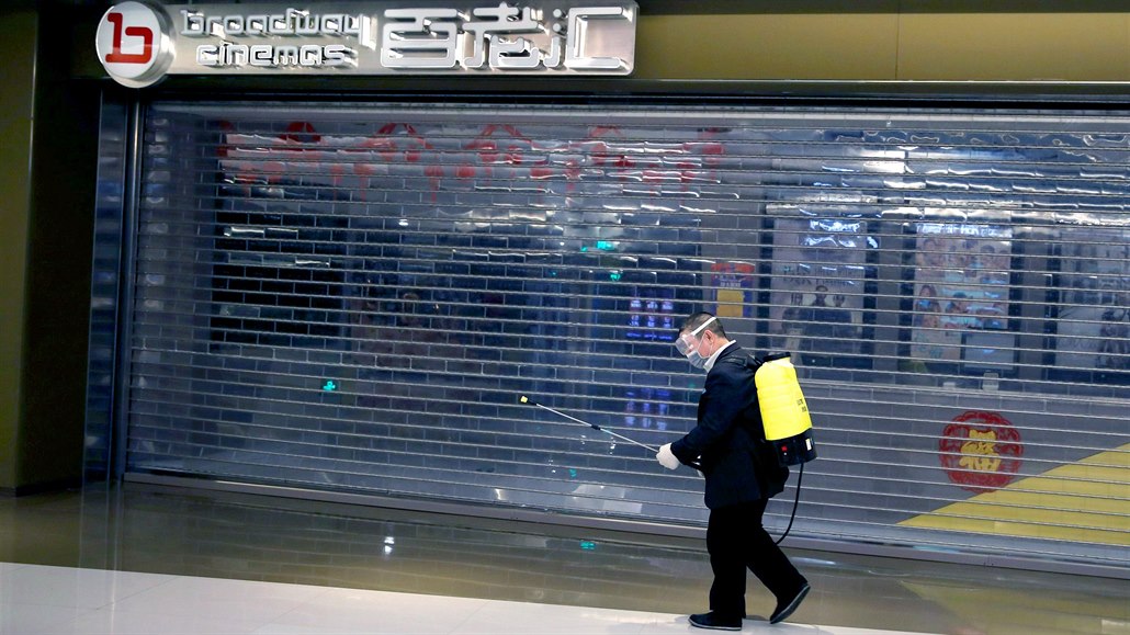 Zaměstnanec nákupního střediska v čínském Pekingu dezinfikuje okolí uzavřeného...