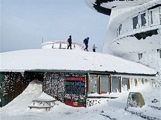Turisté lezou na střechu meteostanice na Sněžce.