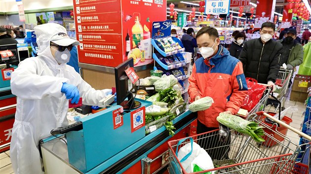 Pracovník obchodního domu v ochranném obleku obsluhuje zákazníky v čínském městě Wu-chan. Právě zde vypukla nákaza koronavirem Covid-19. (12. února 2020)