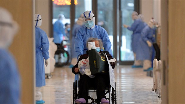 Zdravotnk v ochrannm obleku veze pacientku na kolekovm kesle v nemocnici v nskm mst Wu-chan. Prv zde vypukla nkaza koronavirem Covid-19. (10. nora 2020)