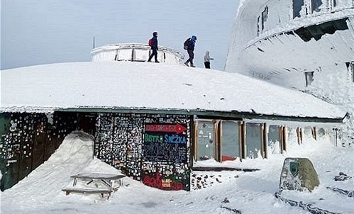 Turisté lezou na střechu meteostanice na Sněžce.