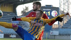 Úto�ník Luká� �elezník (vp�edu) z Opavy bojuje o mí� s t�ineckým obráncem...