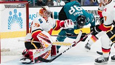 Branká Calgary David Rittich zasahuje, ped ním Brent Burns ze San Jose.