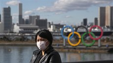 Turistka pózuje v Tokiu ped olympijskými kruhy s ochrannou roukou na tvái.