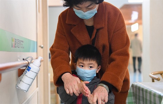 Žena dezinfikuje ruce chlapci v čínském městě Čchang-ša. (25. února 2020)