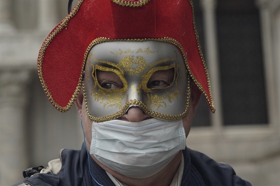 Turista v italských Benátkách má kromě karnevalové masky také respirační roušku...