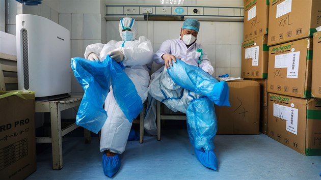 Zdravotnci nemocnice ervenho ke ve Wu-chanu si ppravn mstnosti oblkaj ochrann obleky. (24. nora 2020)