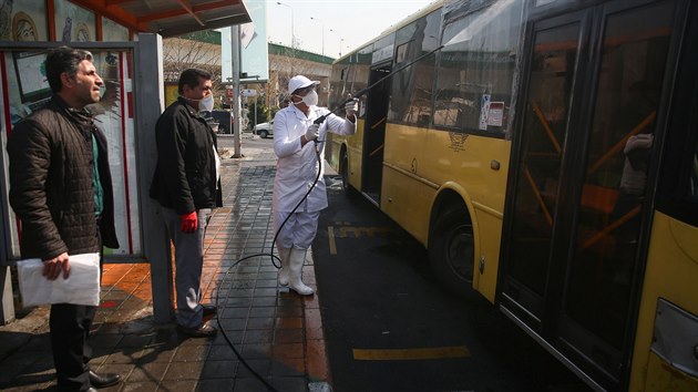 Zdravotník v ochranném oděvu dezinfikuje autobus v íránském hlavním městě Teheránu. (6. března 2020)