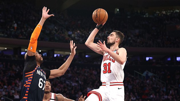 Tom Satoransk z Chicaga pi stelb, blokuje ho Taj Gibson z New York Knicks.