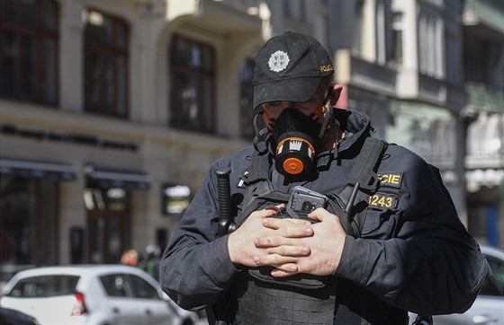 Policista hlídkuje se speciálním respirátorem v centru Prahy. (14. bezna 2020)