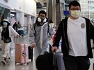 Cestující z Londýna nosí ochranný odv proti koronaviru na mezinárodním letiti...