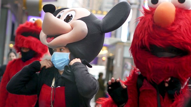 Žena pracující na newyorském Times Square v kostýmu Mickey Mouse si navlékla ochrannou roušku. (10. března 2020)