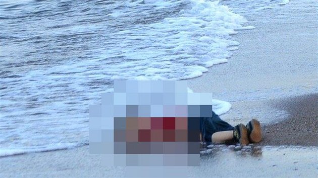 Turecký policejní důstojník stojí vedle mrtvého těla Alana Kurdího u pobřeží v Bodrumu v jižním Turecku. (2. září 2015)