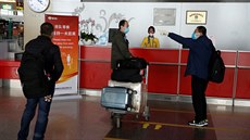 Lidé s ochrannými roukami na letiti v Pekingu. ína nyní eviduje více pípad...