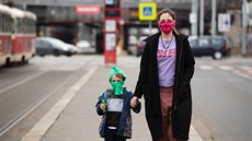 Lidé na tramvajové zastávce nosí ochranné rouky. Od verejka platí v Praze a...