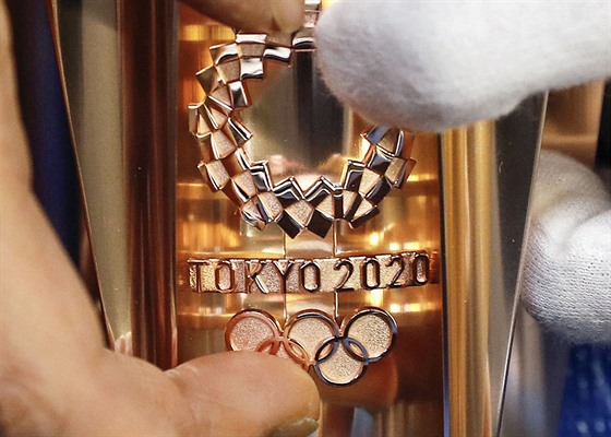 Logo olympijských her v Tokiu 2020 na pochodni s olympijským ohněm