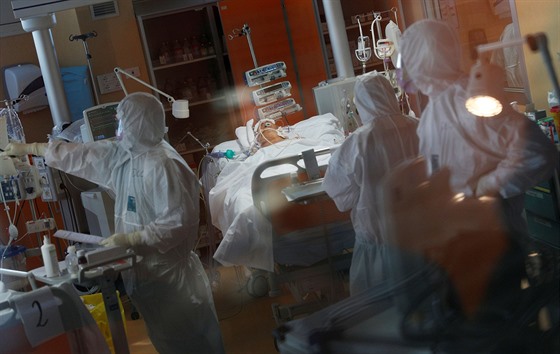Zdravotníci v ochranných oděvech se starají o pacienta nakaženého koronavirem....