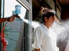 Zaměstnanec kavárny v myanmarském Rangúnu dezinfikuje jednu ze zákaznic. (26....