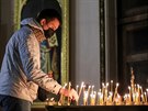 Rus v rouce zapaluje svíky v kostele. Rutí vící navtvují bohosluby...