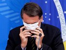 Brazilský prezident Jair Bolsonaro bojuje s ochrannou roukou bhem tiskové...