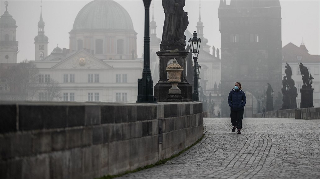 Turistka prochází po oputném Karlov most v Praze. (18. bezna 2020)