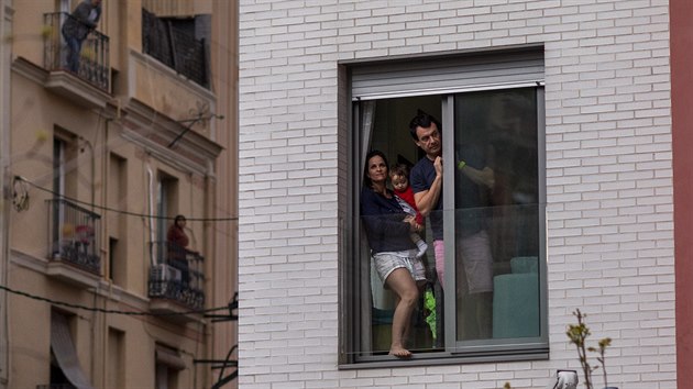 Obyvatelé Madridu vyhlížejí z oken svých bytů. V rámci opatření proti šíření koronaviru mají Španělé až na výjimky zákaz pobytu na veřejném prostranství. (29. března 2020)