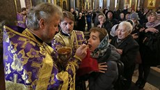 Kní v pravoslavné katedrále v ruském Petrohradu udílí vícím svaté pijímání...