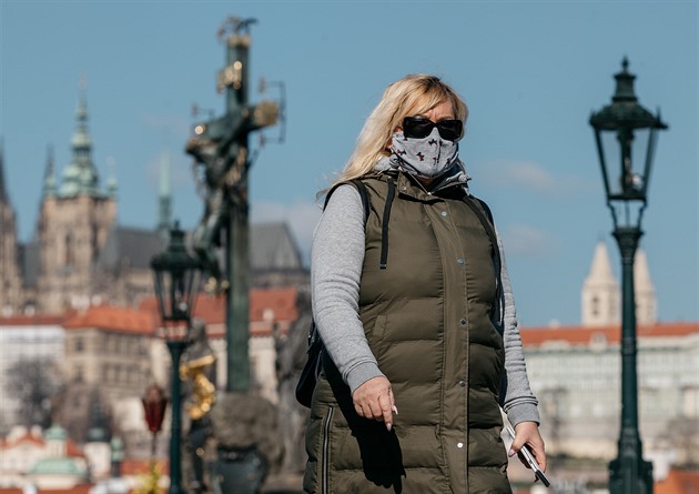 Žena v roušce při procházce přes Karlův most v Praze. (1. dubna 2020)