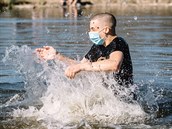 Mladíci v rouškách dovádějí v rybníku v pražské Stromovce. (8. dubna 2020)