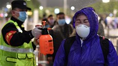 Policista dezinfikuje cestující p�ed nádra�ím ve Wu-chanu. M�sto po více jak...