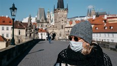 Žena v roušce při procházce přes Karlův most v Praze. (1. dubna 2020)