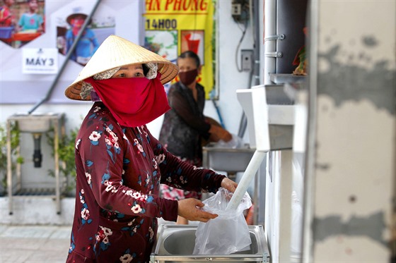 Žena s igelitovým sáčkem čeká na příděl rýže zdarma u automatu v Ho Či Minově...