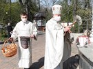 Knz ukrajinské eckokatolické církve kropí svcenou vodou velikononí koláky...