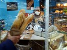 Prodavaka v pekárn na pedmstí Paíe se chrání proti nákaze plastovou...