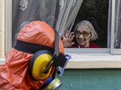 Seniorka zdraví pracovníka, který provádí dezinfekci ulice v Santiagu, hlavním...