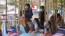 Lidé s roukami proti koronaviru si uívají v tchajwanském zábavním parku. (11....