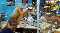 Prodavaka v pekárn na pedmstí Paíe se chrání proti nákaze plastovou...