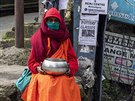 Buddhistický mnich v rouce sedí na námstí a ebrá o almunu v Dharmsale v...