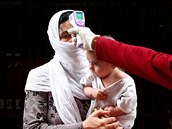 Indický lékař měří teplotu matce s dítětem v rezidenční čtvrti v Novém Dillí....
