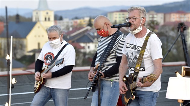 Zprava zpěvák Petr Fiala a kytaristé Jaromír Mikel a Martin Knor při vystoupení skupiny Mňága a Žďorp na střeše hotelu Apollo ve Valašském Meziříčí. (18. dubna 2020)