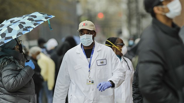 Newyorsk zdravotnk prochz kolem fronty lid ekajcch na testy na koronavirus. (23. dubna 2020)