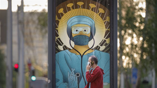 Rumun přechází kolem plakátu, zobrazujícího zdravotníka jako světce. Kampaň pobouřila rumunskou pravoslavnou církev, mluví o rouhání. (29. dubna 2020)