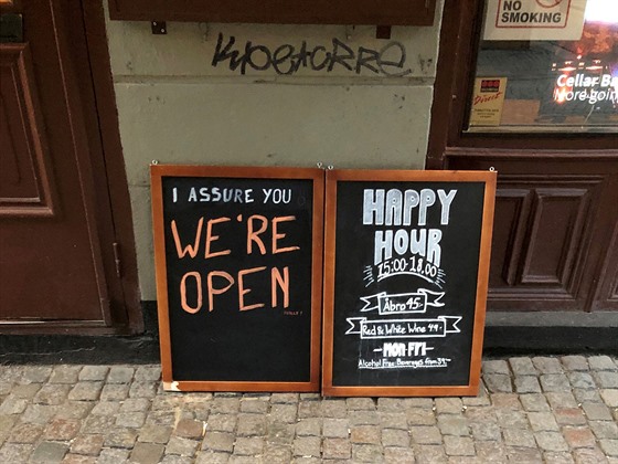 Cedule před barem v hlavním městě Stockholmu upozorňuje lidi, že je otevřeno....