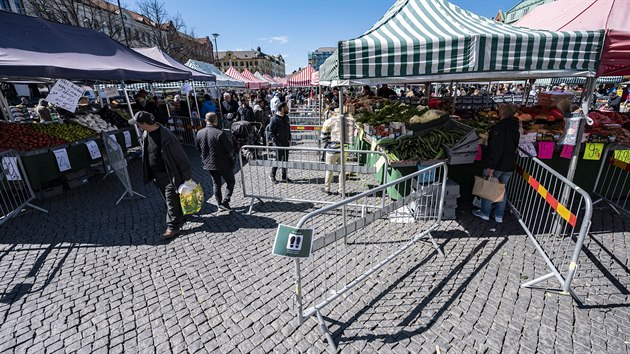 Lidé čekají ve frontě za přepážkami, které mají omezit fyzický kontakt mezi lidmi a usměrňovat pohyb davu. Jde o farmářské trhy ve švédském městě Malmö. 25. dubna 2020